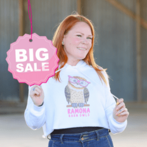 Young woman wearing white cropped hoodie with pink owl logo (sale).