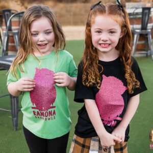Two girls in black/green shirts with pink glitter owl design.